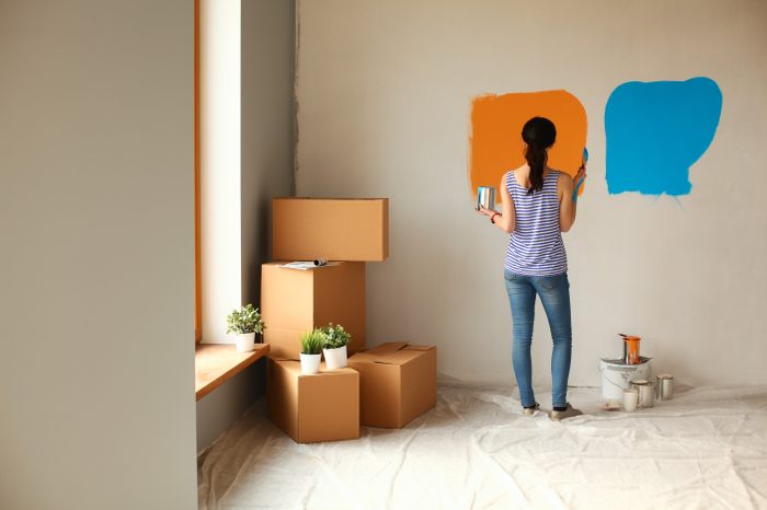 Happy smiling woman painting interior wall of new house