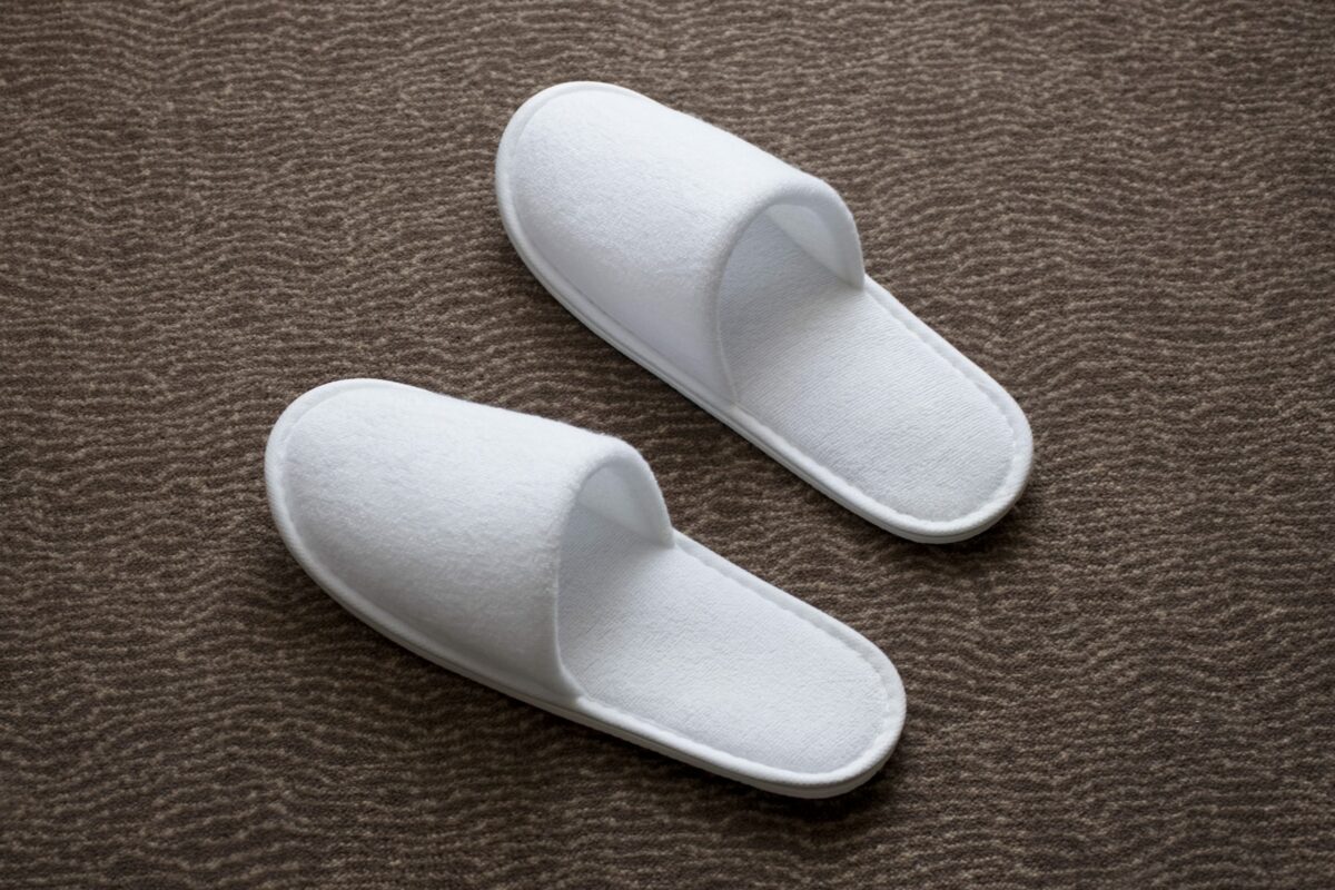 White slippers resting on a textured brown carpet surface.