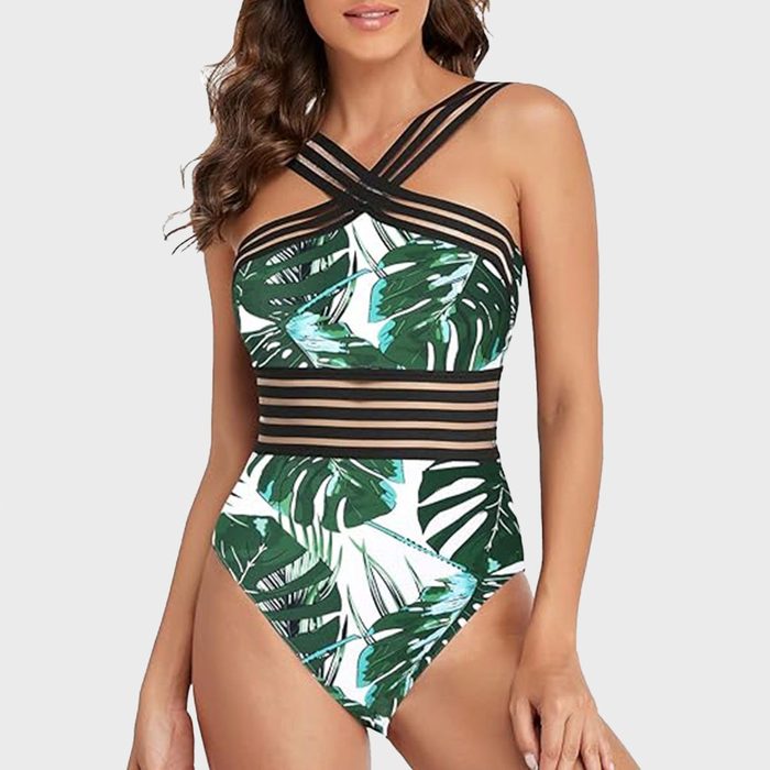 Swimsuit displayed on a model, featuring green leaf patterns and striped black accents. The background is plain white.