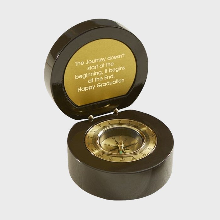 Compass sits in a round, open case with gold interior. Inscription reads, 