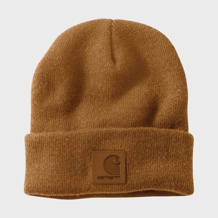 A brown knit beanie is displayed with a folded edge, featuring a leather patch logo in a plain, neutral background.